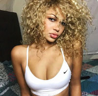 Blond, curly haired Latina in a white top showing cleavage